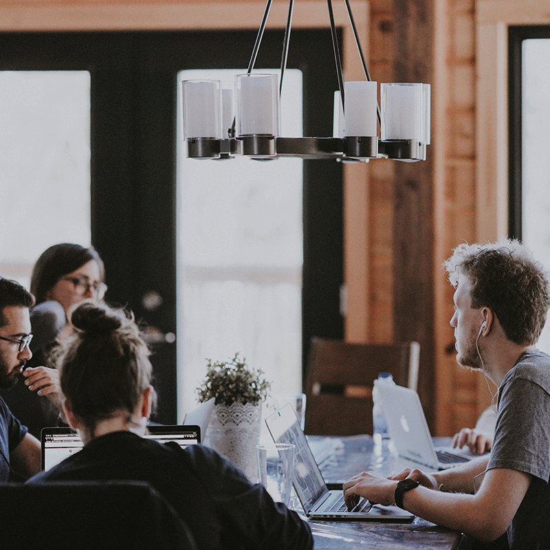 Group of people around a table with laptops